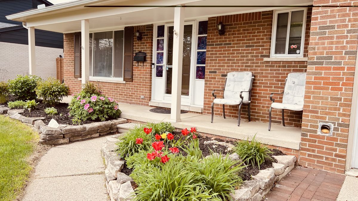 Covered front porch with seating and colorful tulip flower beds