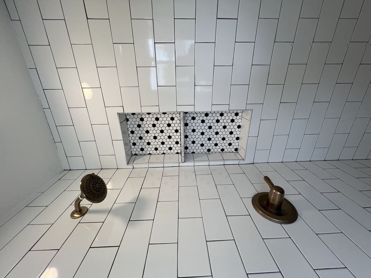 Primary bath — granite vanity with round mirror and vertical tile accent